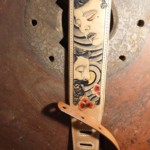 Détail visages sur une sangle de guitare